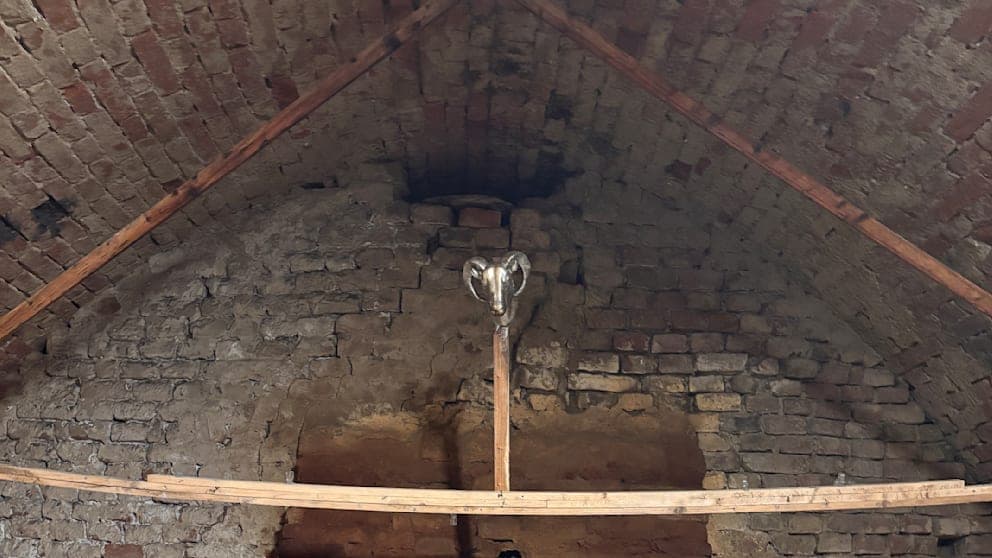 Ein rätselhaftes Holzlatten-Dreieck im Keller trägt in seiner Mitte den silbernen Kopf eines Ziegenbocks.