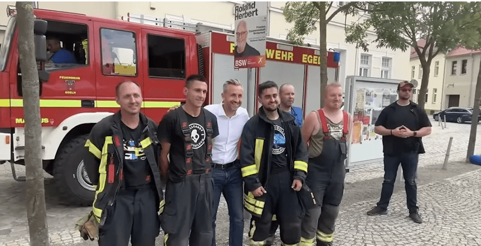 Feuerwehrleute in Uniform am Wahlkampfstand von Ulrich Siegmund – das Bild erzürnt die Gemüter.